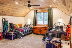 A cozy bedroom with two metal bunk beds, a wooden ceiling, a window with curtains, and a dresser. - Off-Grid Mountain Cabin w/ Deck & Divide Views (Jefferson)