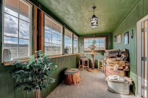 Ein gemütliches Blockhaus mit großen Fenstern, einem Holztisch, Stühlen und einem Blumentopf.