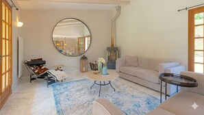 Ein gemütliches Wohnzimmer mit einem runden Spiegel, einem Sofa, einem Couchtisch und einem Kamin.