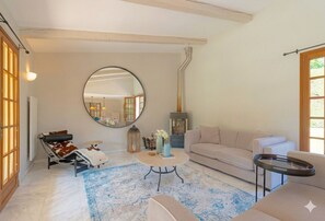 Ein gemütliches Wohnzimmer mit einem runden Spiegel, einem Sofa, einem Couchtisch und einem Kamin.