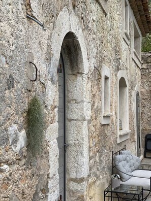 A stone building with arched windows and a bed with a white duvet and a pillow. - Magnifique Maison historique (Saint Paul de Vence)