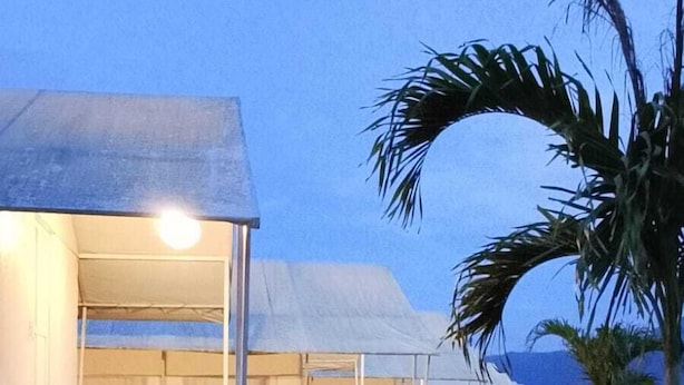 A row of white tents with a wooden deck in front, surrounded by grass and palm trees. - Ohara Glamping (Kintamani)