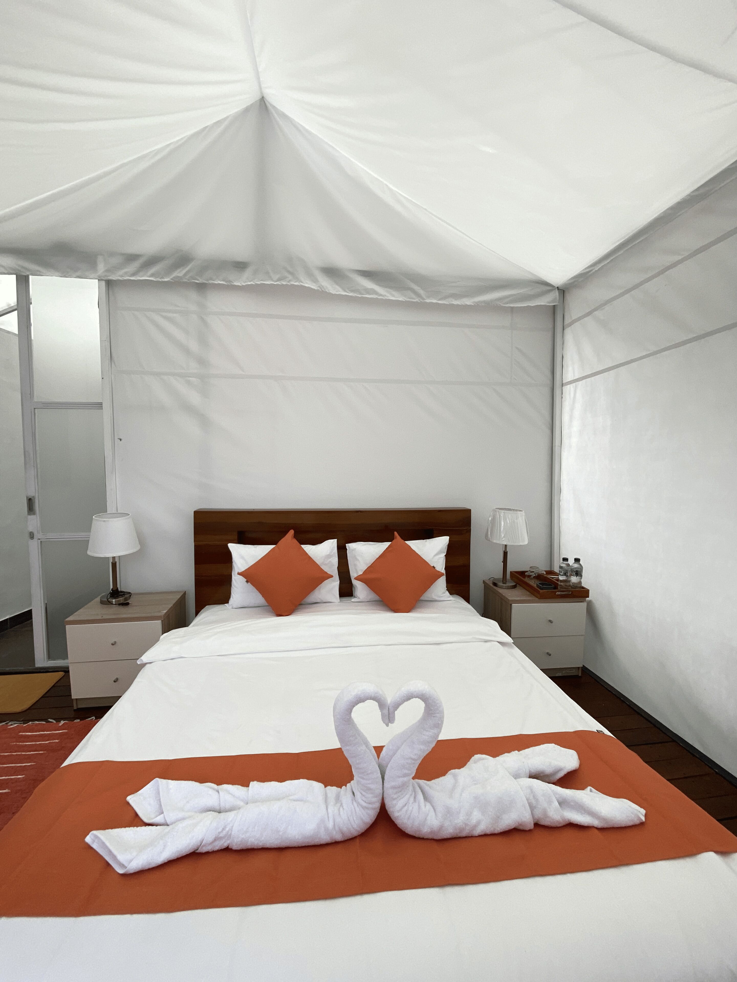 Een hotelkamer met een groot bed, twee nachtkastjes, een houten hoofdeinde en een tentachtige hemelbed.