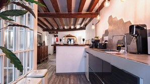 Une cuisine moderne avec des poutres en bois, un îlot central et une vue sur l’espace repas.