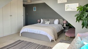 Een slaapkamer met een bed, nachtkastje, een bloempot en een deur.