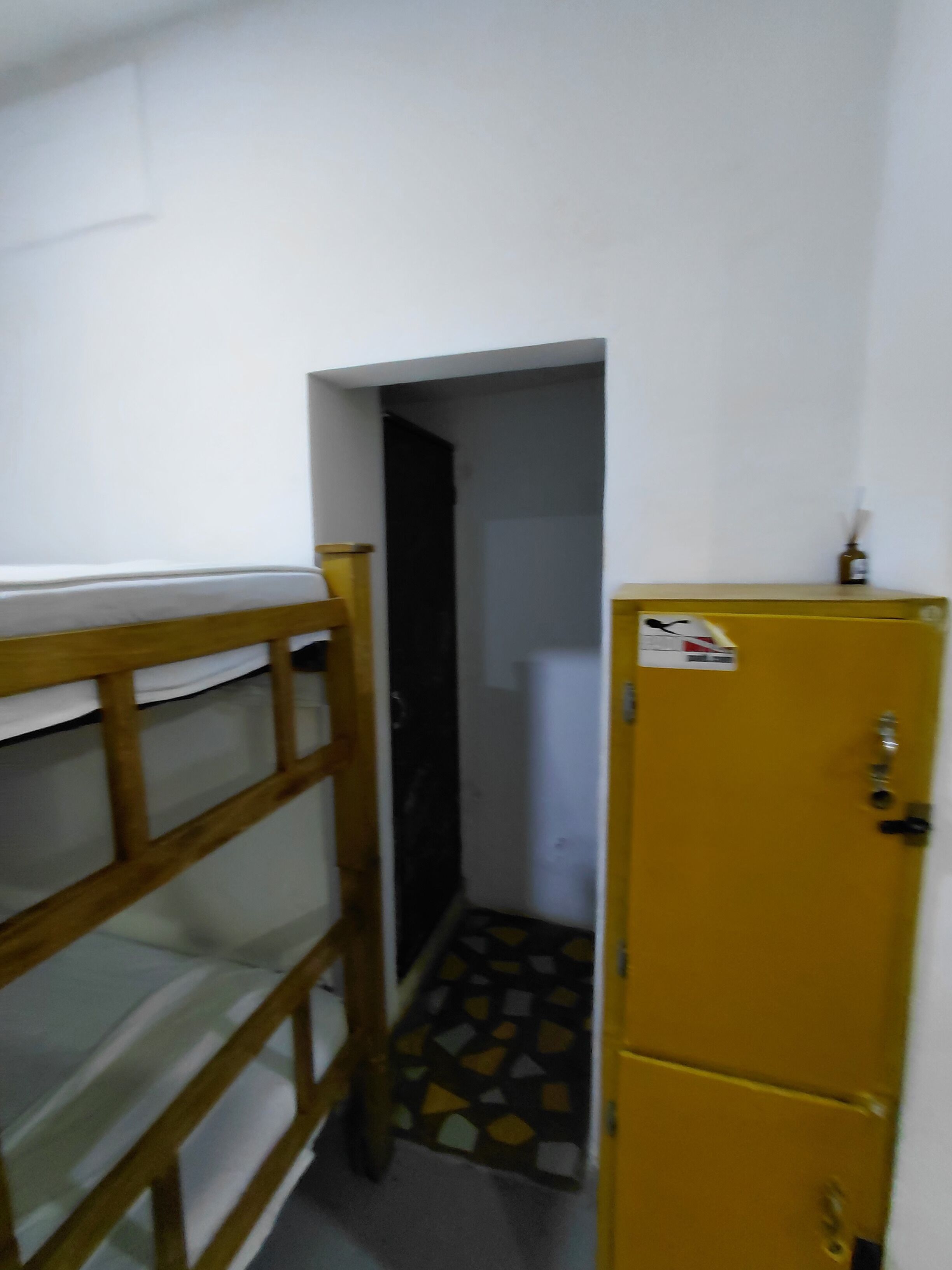 A narrow hallway with a bunk bed on the left and a yellow storage unit on the right.