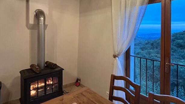 Ein Essbereich mit Kaminofen, einem Tisch mit Speisen und Blick ins Freie.