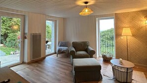 Ein geräumiges Zimmer mit Holzbalkendecke, einer Couch, einem Tisch und einer Lampe.