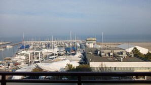 A marina with numerous boats docked, a control tower, and a building with a flat roof. - CV020 – Cervia, penthouse with stunning sea view (Cervia)