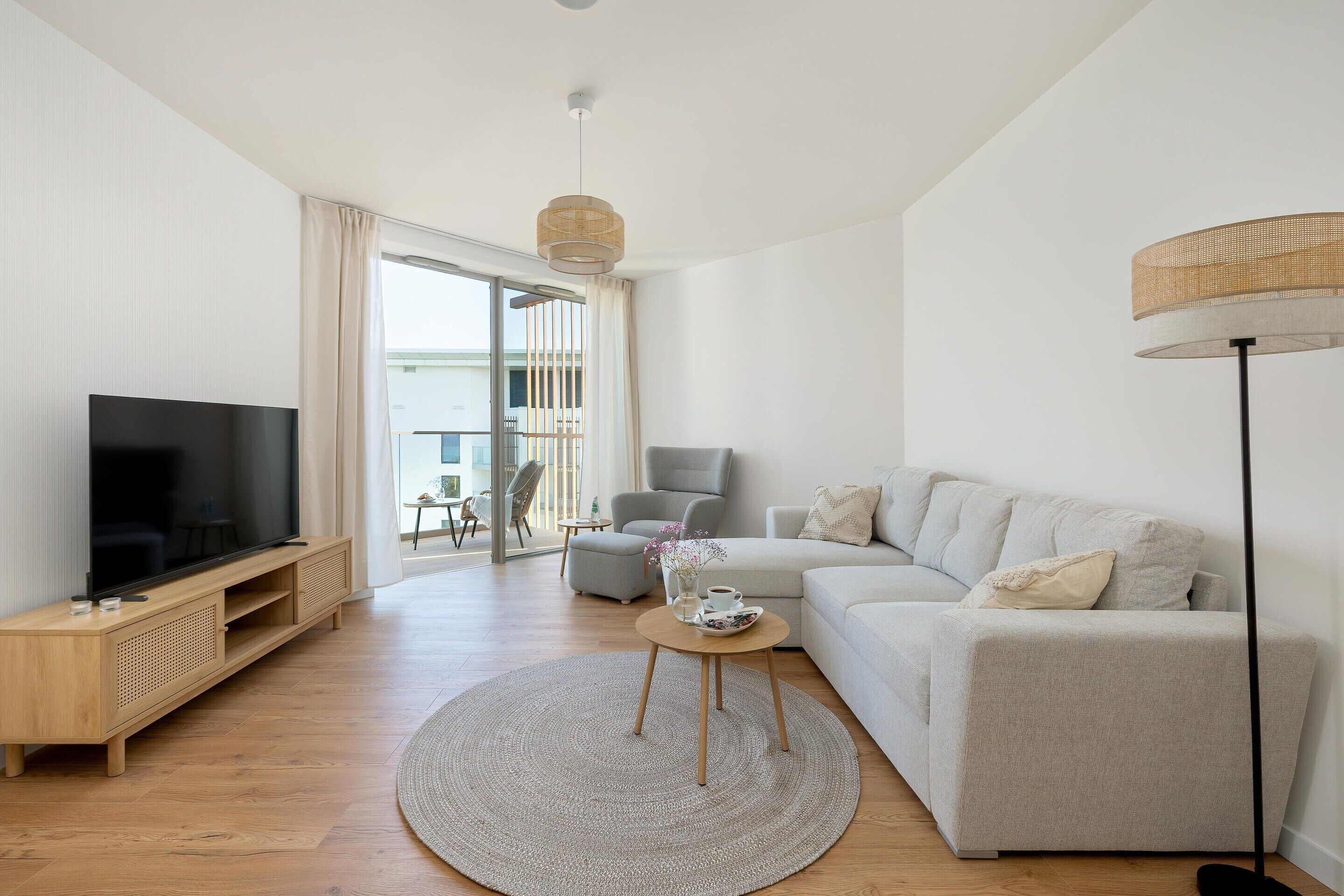 Un salon moderne avec un téléviseur à écran plat, un canapé, une table basse et un lampadaire.