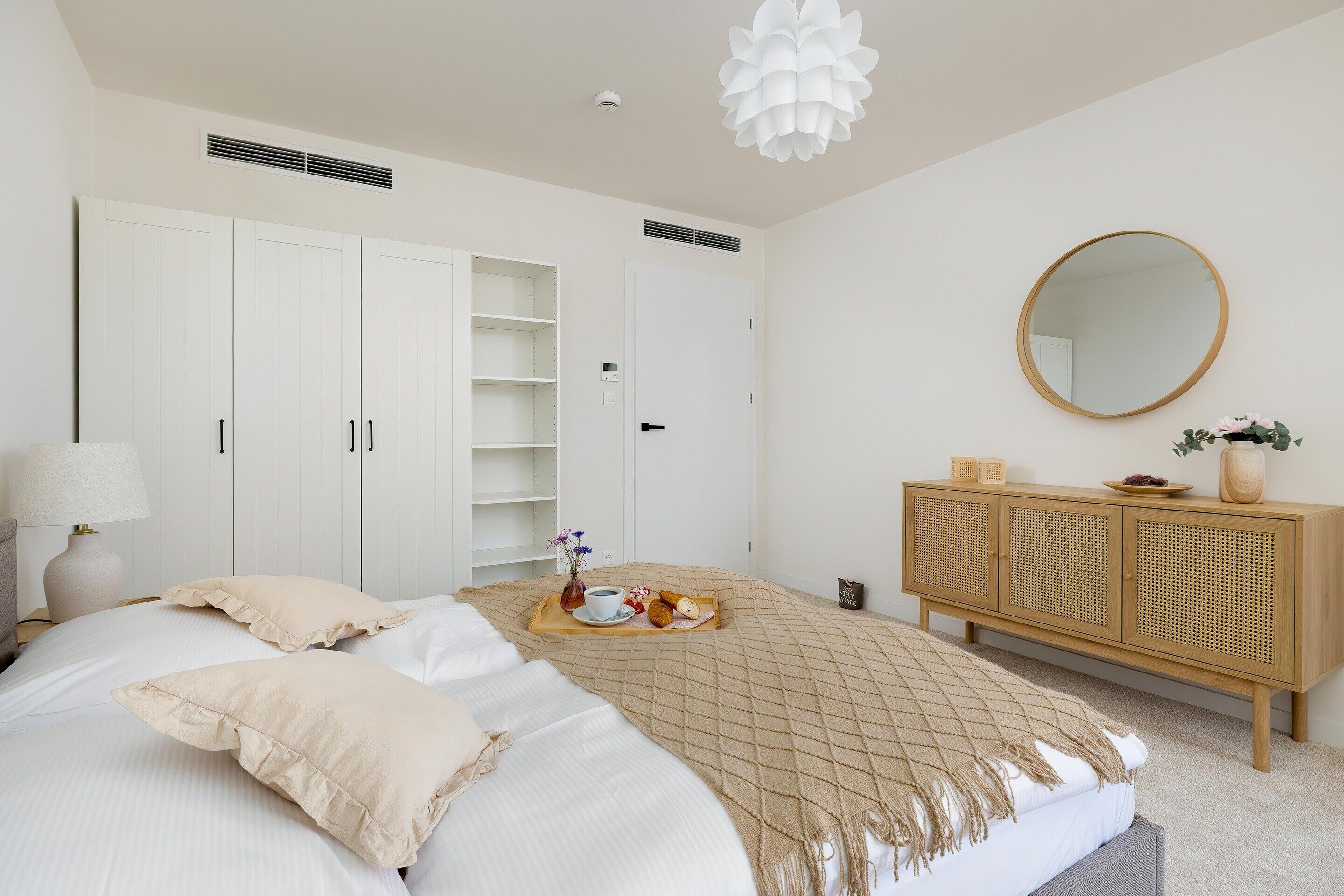 A bedroom with a bed, a bedside table, a wardrobe, a mirror, and a cabinet.