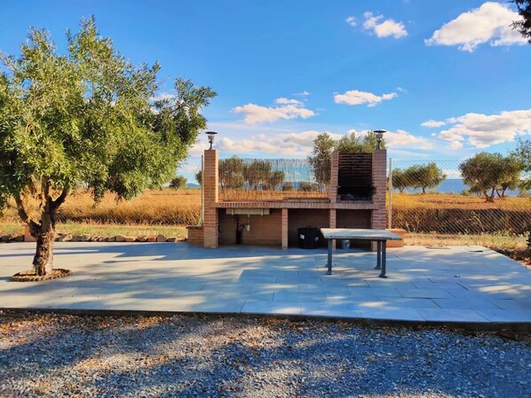 An outdoor barbecue area with a brick oven, a table, and a pergola.