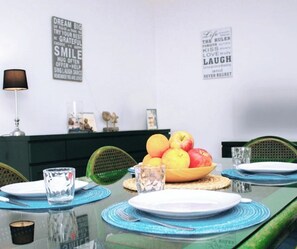 A dining table with a fruit bowl, plates, and glasses, set against a wall with motivational quotes.
