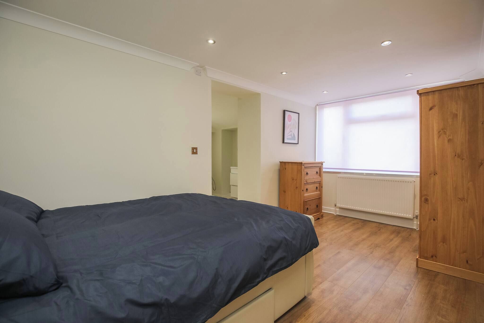 A bedroom with a bed, wooden wardrobe, and a radiator.