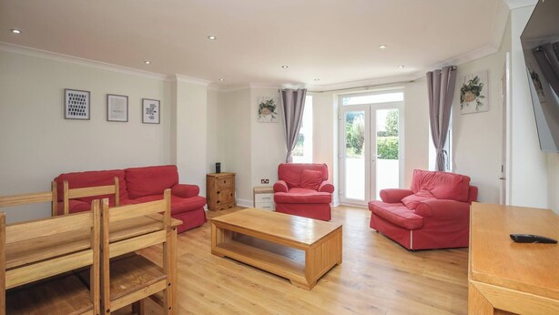 A spacious living room with a wooden floor, red sofas, a wooden coffee table, and a wooden TV stand. - Charming Central Kingston Flat by the River (Kingston Upon Thames)