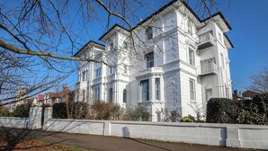 A white, multi-story building with a symmetrical facade, large windows, and a prominent entrance. - Charming Central Kingston Flat by the River (Kingston Upon Thames)