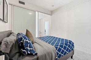 A bedroom with a bed, a grey sofa, and a large mirror. - Cityscape Haven 2BR with Fantastic CN Tower View (Toronto)