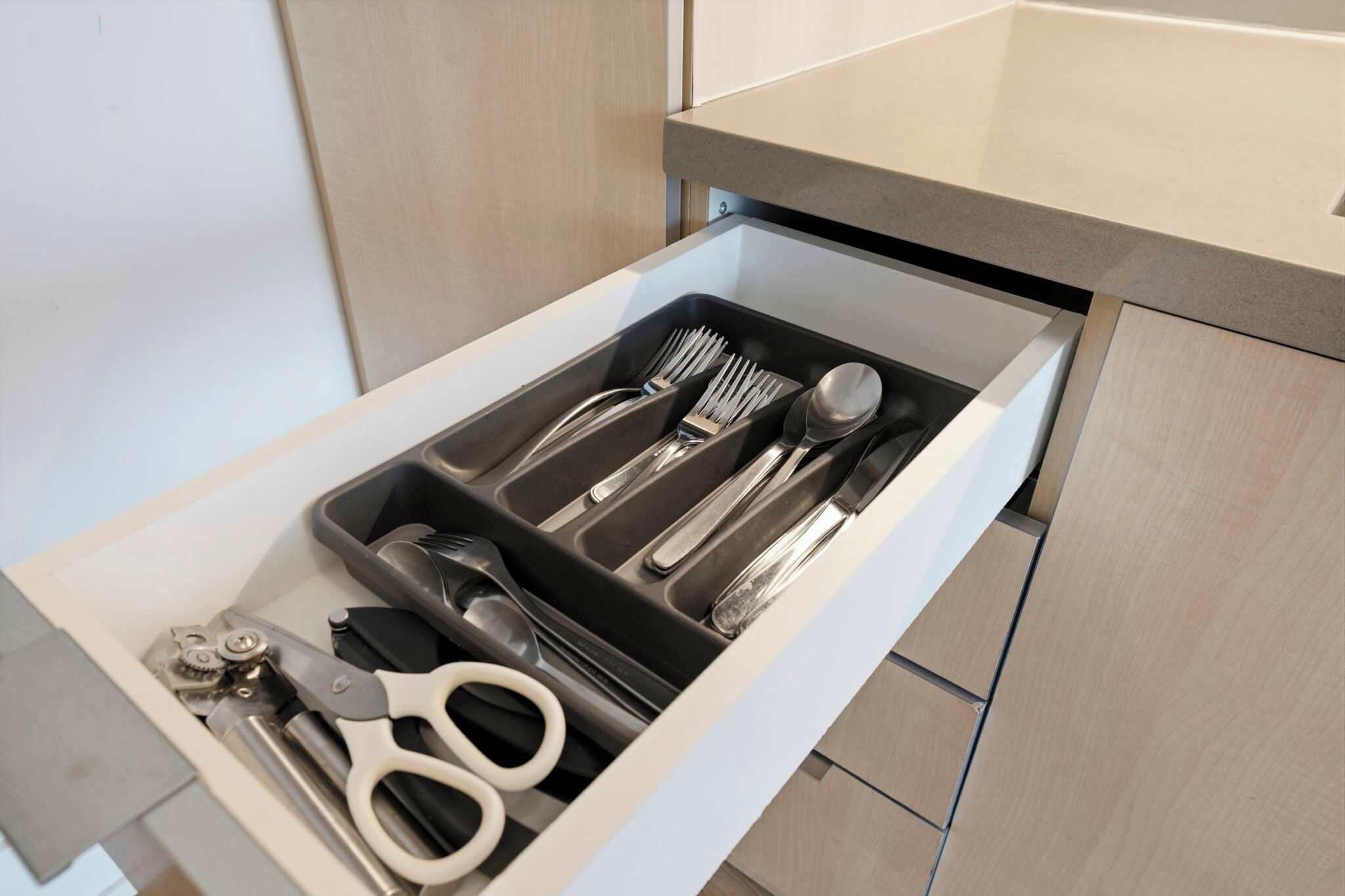 A drawer with utensils and scissors.