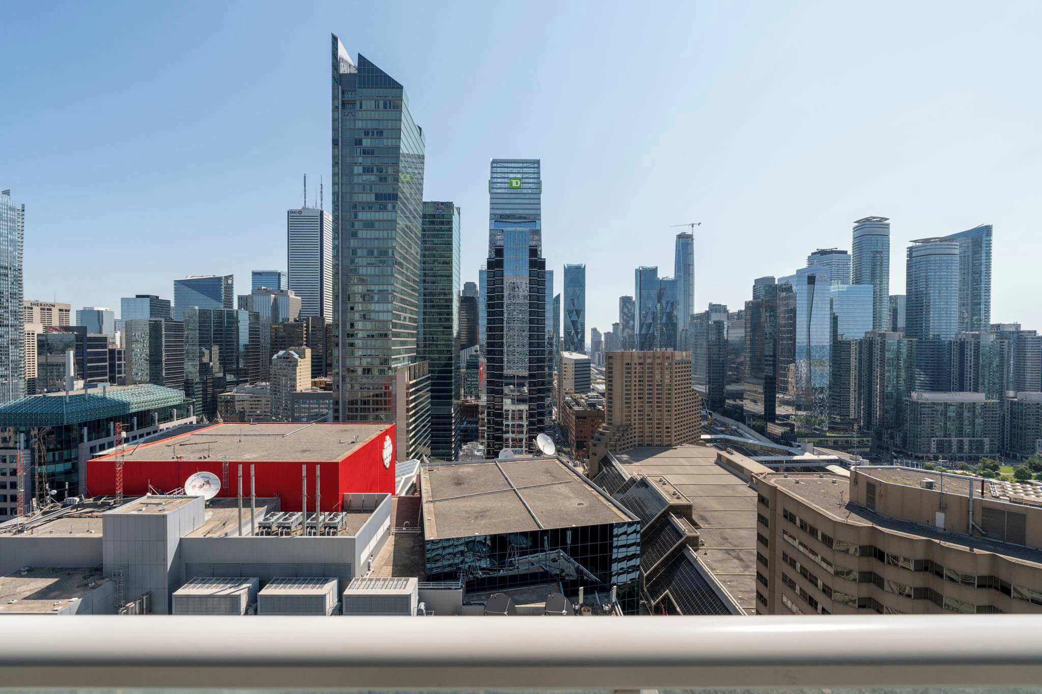 A cityscape with modern skyscrapers, a red building, and a rooftop with satellite dishes.