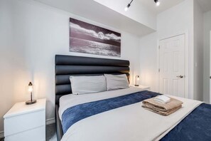 The bedroom, adorned with tasteful decor, is centered around a luxurious king-size bed, inviting rest and relaxation in a haven of comfort and style. - Modern 1BR/1BA condo near Downtown with City Views (Toronto)