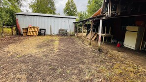 A rural property with a metal shed, wooden structures, and a dirt yard. - Black Stone (Licanray)