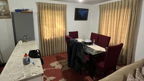 A hotel room with a dining area, a sofa, a small table with a bottle and a cap, and a picture on the wall. - Black Stone (Licanray)