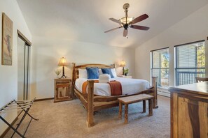 Ein Schlafzimmer mit einem hölzernen Bett, zwei Nachttischen mit Lampen, einem Deckenventilator und großen Fenstern mit Jalousien.