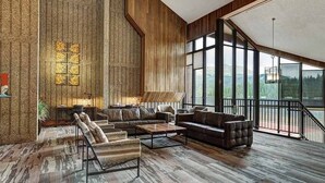 Ein geräumiges Wohnzimmer mit großem Fenster, Kamin und einer Treppe, die in einen oberen Bereich führt.