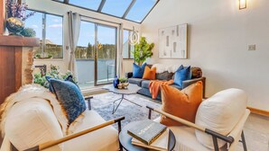 Ein modernes Wohnzimmer mit einem großen Oberlicht, einer Sofagarnitur, einem Couchtisch und einem Bücherregal.
