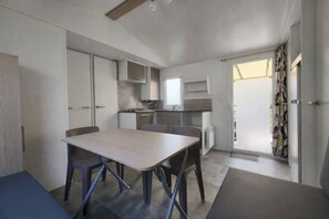 Eine moderne Küche mit Esstisch und Stühlen, einem eingebauten Backofen und einem Fenster, das für natürliches Licht sorgt.