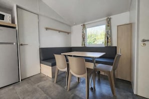 Eine kompakte Küchenzeile mit Mikrowelle, einer eingebauten Sitzbank und einem fenster mit Vorhängen.
