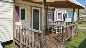 A mobile home with a covered porch, a dining table, and chairs. - 3-bedroom mobile home near the ocean + pool (Saint-Georges-de-Didonne)
