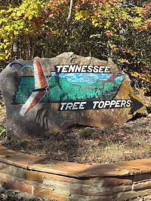 A large rock with a painted airplane and the words "Tennessee Tree Toppers" on it.