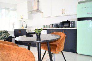 A modern kitchen with white cabinets, a green refrigerator, and a round table with two chairs. - Luxurious 6bd Apt, Wifi, Ensuite, outdoor area (Birmingham)