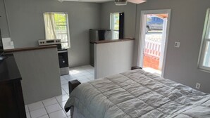 Quarto com cama, escrivaninha, ventilador de teto e janela.