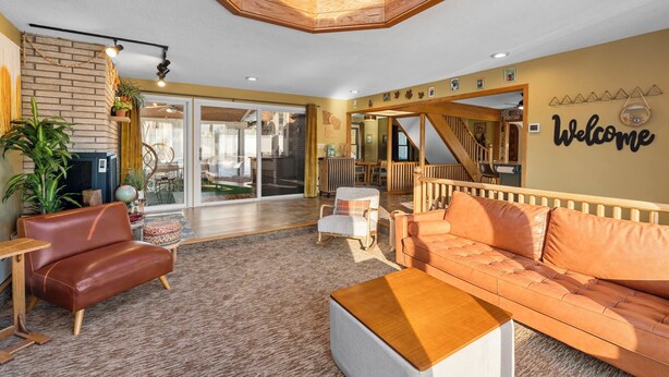 A spacious living area with a high ceiling, a wooden staircase, and a 'Welcome' sign on the wall. - Maplewood Getaway | Sauna & Bar (Maplewood)