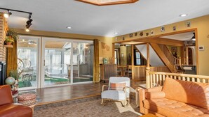 A spacious living room with a large skylight, a staircase, and a view of the outdoors. - Maplewood Getaway | Sauna & Bar (Maplewood)