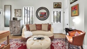Un salon comprenant un canapé, un pouf et une table en bois. On y trouve également un meuble et une chaise.