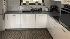 Eine moderne Küche mit weißen Schränken, einer Edelstahl-Spüle und einem eingebauten Backofen.