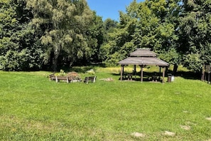 A gazebo in a grassy field with trees in the background. - Holiday Home, Large Garden With Playground, Gazebo (Ustka)