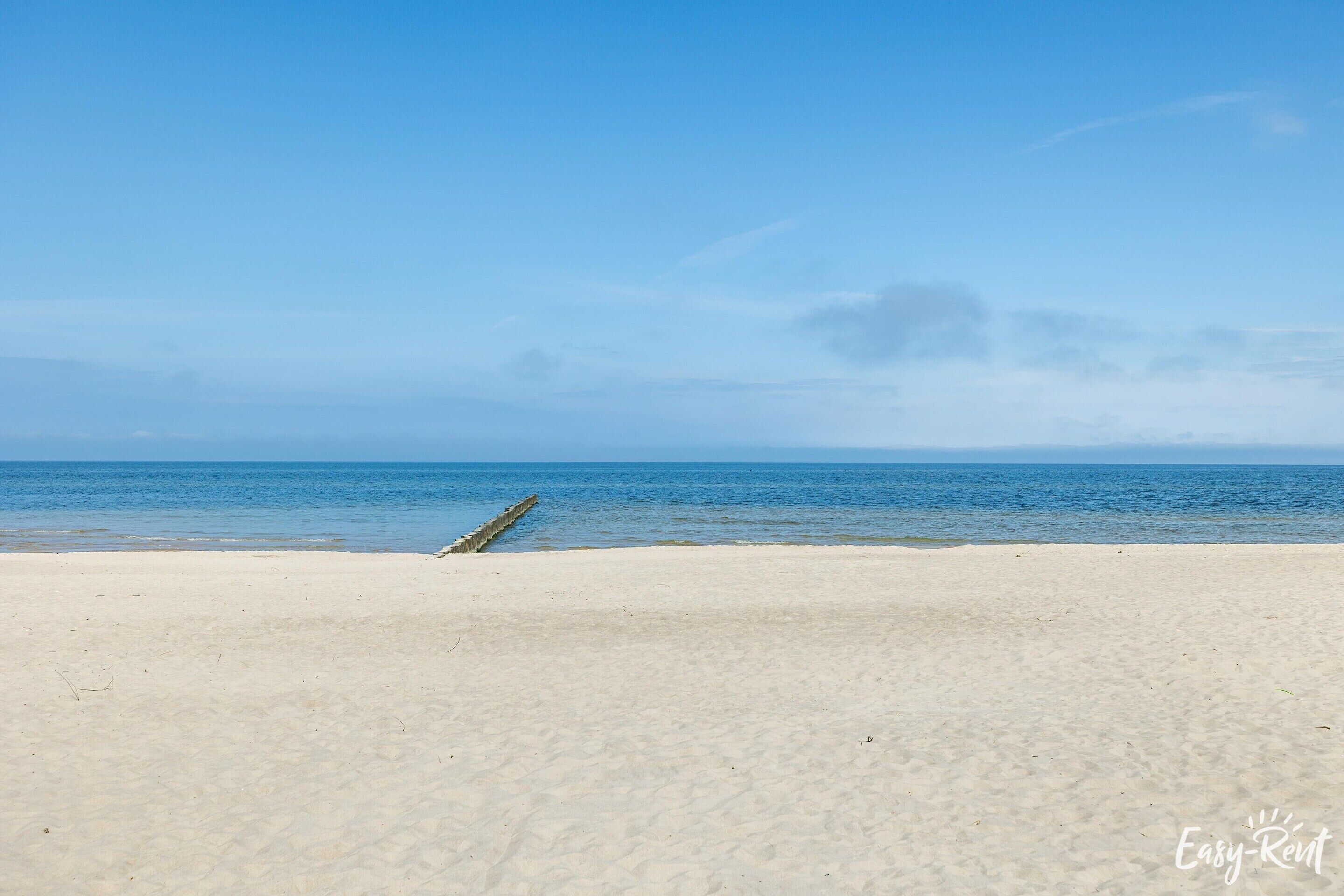 En strand med klart skys og roligt hav.