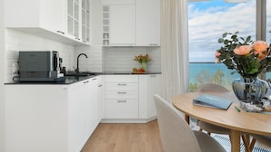 A modern kitchen with white cabinetry, a coffee machine, and a view of the sea through a large window. - Stunning Seaview Retreat for 4 in Pobierowo (Rewal)