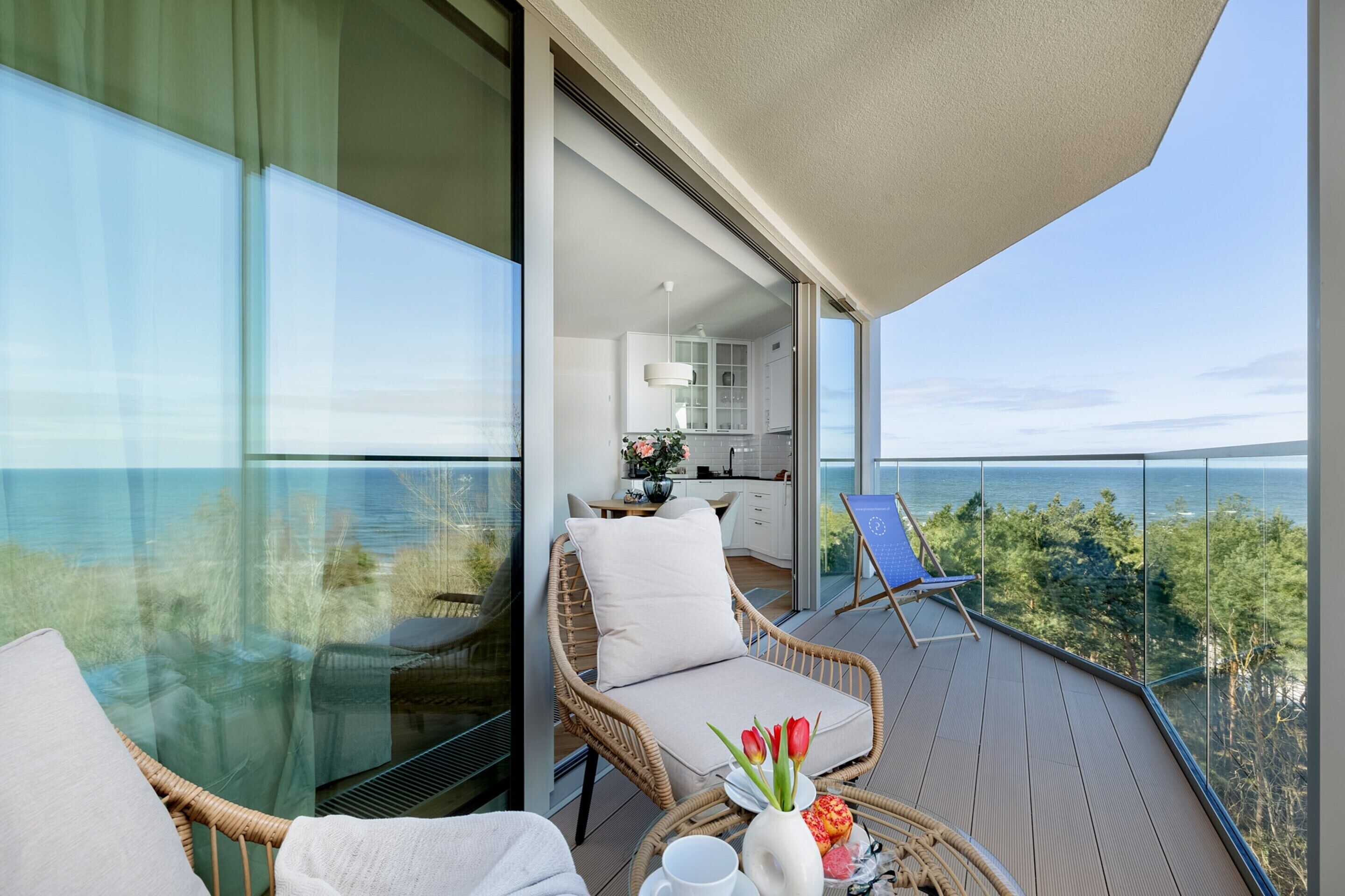En balkon med fletmøbler, et spiseområde og havudsigt.
