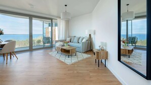 A modern living room with a sofa, coffee table, and side table, large windows with a view of the sea, and a dining area with chairs. - Stunning Seaview Retreat for 4 in Pobierowo (Rewal)