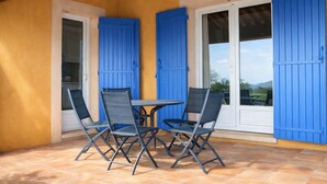 A patio with a table and four chairs, blue shutters, and a view of the outdoors. - Genièvre apartment in residence with heated pool (Saint-Trinit)