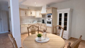 A dining area with a round table, four wooden chairs, a small potted plant, and a tray. - Genièvre apartment in residence with heated pool (Saint-Trinit)