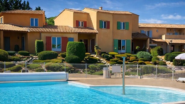 A swimming pool with a clear blue water surface, surrounded by a well-maintained garden with neatly trimmed bushes and a fence. - Genièvre apartment in residence with heated pool (Saint-Trinit)