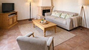 A living room with a sofa, a coffee table, a TV, and a fireplace. - Genièvre apartment in residence with heated pool (Saint-Trinit)