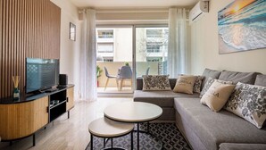 A modern living room with a TV, sofa, and two small tables. - Le Roxane joli cocon avec petit terrasse (Cannes)