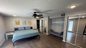 Une chambre à coucher avec un lit, un ventilateur de plafond et un banc.